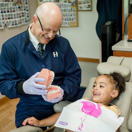 Dr. Hansen showing a young female patient some giant false teeth